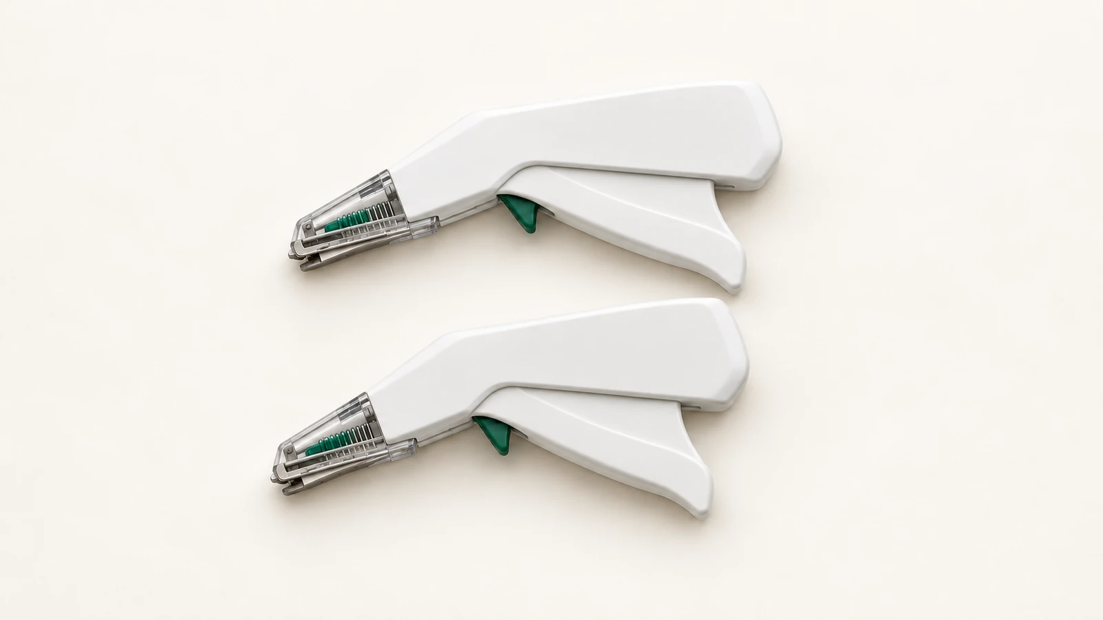 Illustrative still life of two unbranded white disposable skin staplers with green accents and metal cartridge noses on an off-white surface